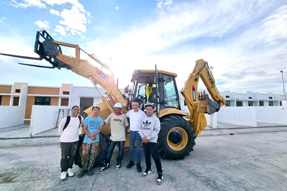 Backhoe loader excavating trenches on a road project in the Philippines